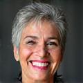 Portrait of Vitalbloom client Maria Rodriguez, 60, smiling warmly.